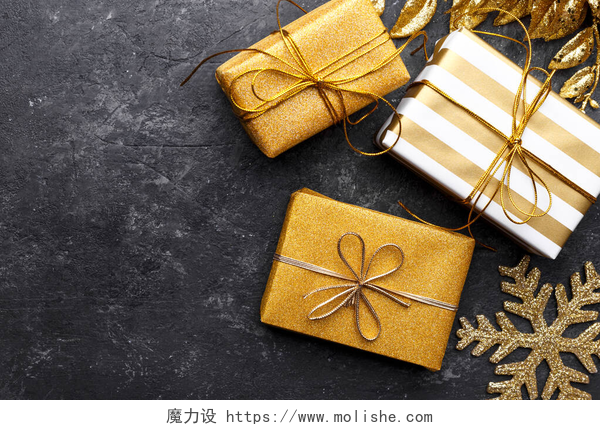 黑色桌子上的礼盒黑色石头背景的金色礼品盒，复制空间平铺，圣诞贺卡